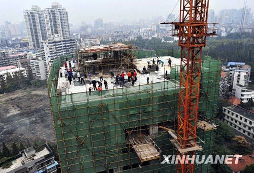 10月27日,工人在违建楼楼顶拆除违章建设楼层。新华社发